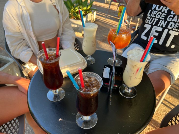 Cocktailabend Die Crew sitzt um den Tisch herum auf dem Cocktails stehen: Pina Colada, Aperol